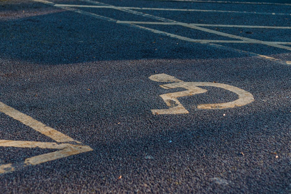 Close-up of a marked parking space on an asphalt surface with a white number '22' painted inside a circle, situated in an outdoor area likely near a property on Locksbottom High Street. The asphalt shows small pebbles and some wear, with adjacent parking line markings visible on the left side. The background suggests a parking lot environment, potentially used by a professional removals service such as Man with Van Locksbottom performing home relocation or furniture transport tasks. The scene captures the typical setting where a van from the company might load or unload furniture, boxes, or appliances, with the parking space prepared for vehicle positioning during a moving or packing and moving process.