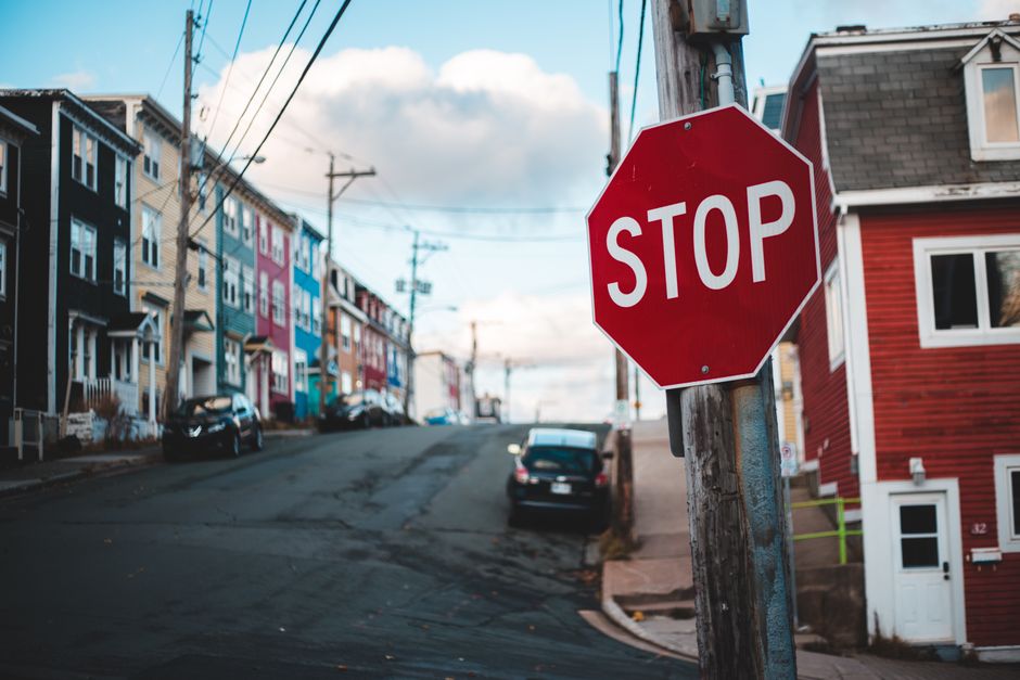 A vertical metal street signpost displaying multiple parking and stopping restrictions. The top sign is red and white, indicating a tow-away zone with no stopping allowed between 3pm and 7pm, except o